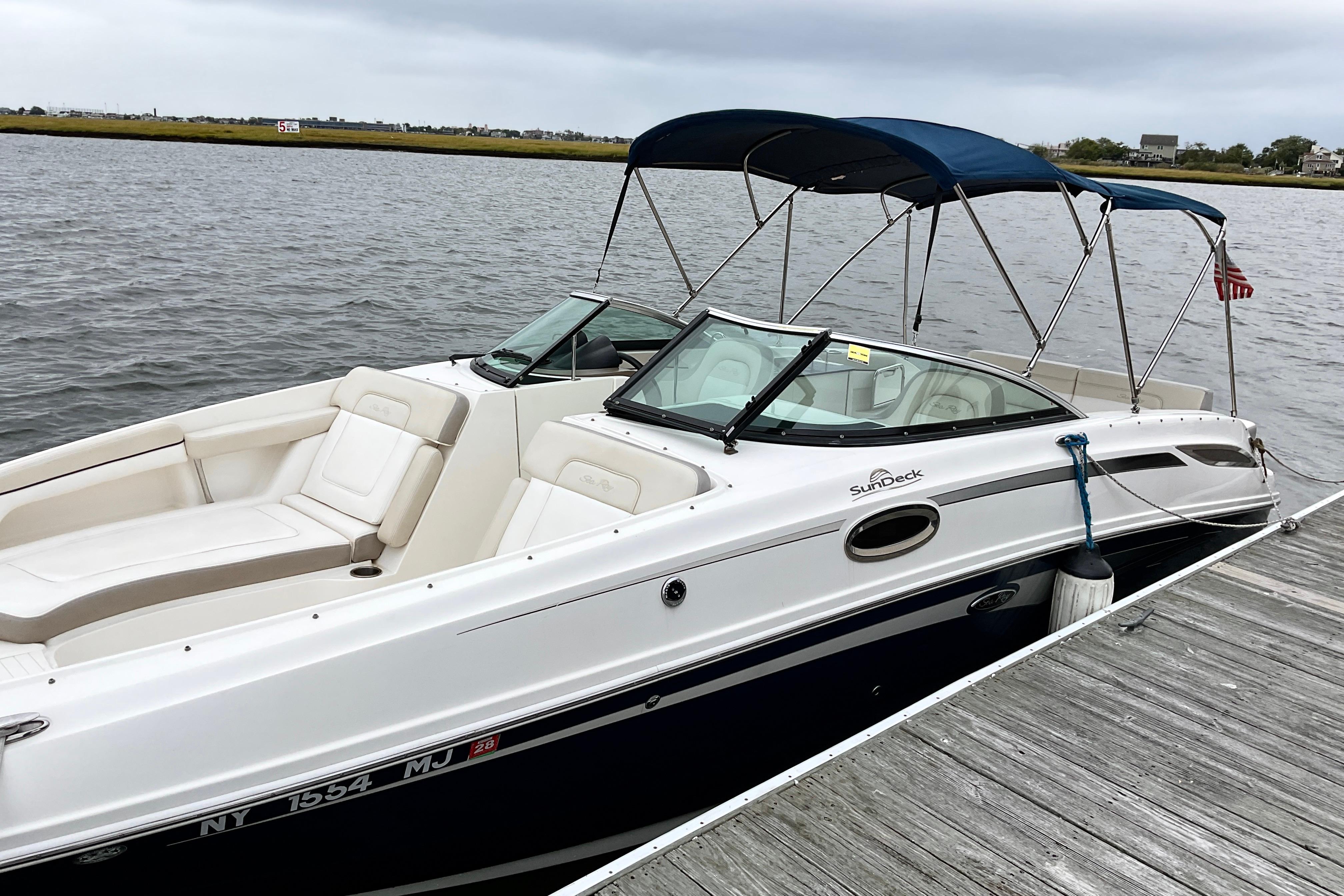 Sea Ray 280 Sundeck 2013 Sea Ray 280 Sundeck boat docked by the water, featuring a blue canopy.