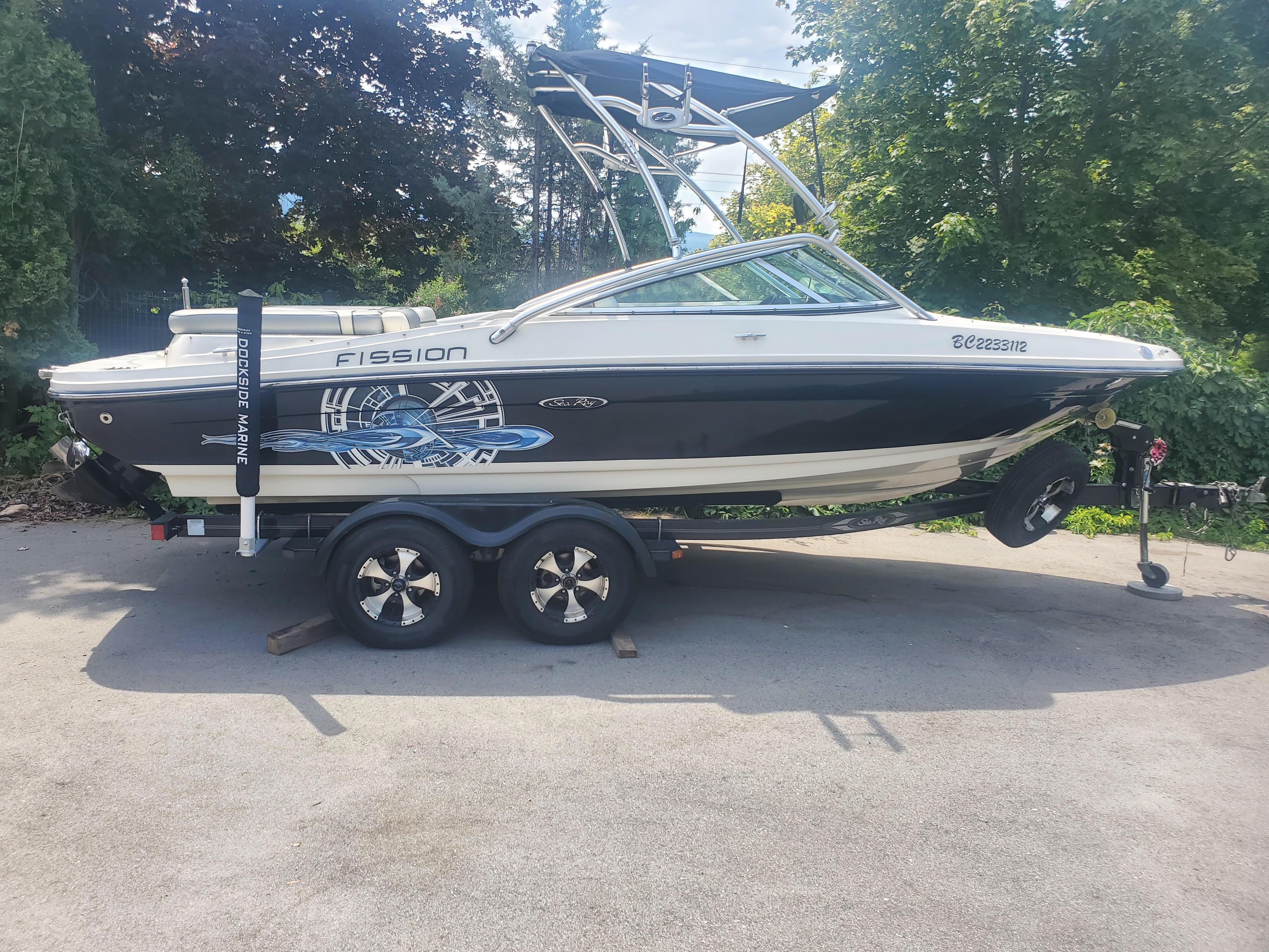 Sea Ray 205 2009 Sea Ray 205 Fission boat on trailer, parked outdoors with trees in background.