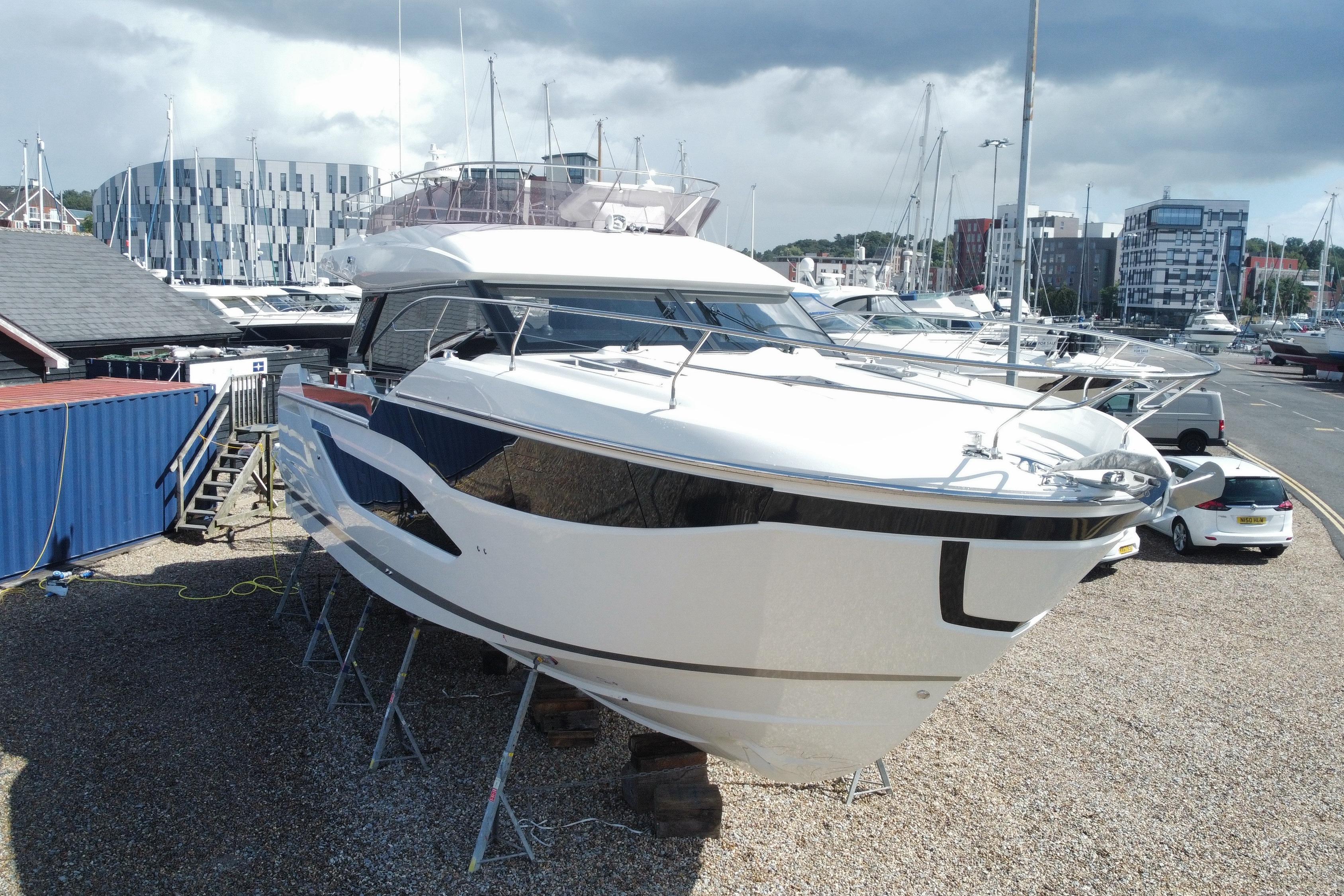 Prestige F4.9 Prestige F4.9 yacht 2025 model on display at a marina with modern buildings.