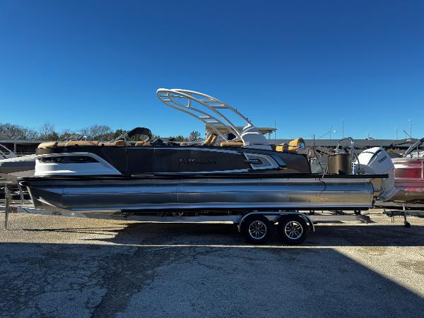 Avalon Excalibur LTD Quad Lounge 2025 Avalon Excalibur LTD Quad Lounge pontoon boat on trailer, under clear blue sky.