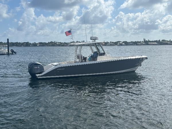 Pursuit S 288 Sport 2022 Pursuit S 288 boat on calm water with American flag, under cloudy sky.