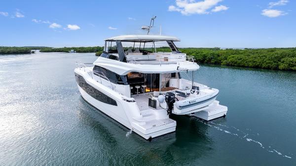 Aquila 50 Yacht Aquila 50 Yacht 2026 cruising on a serene waterway under a clear blue sky.