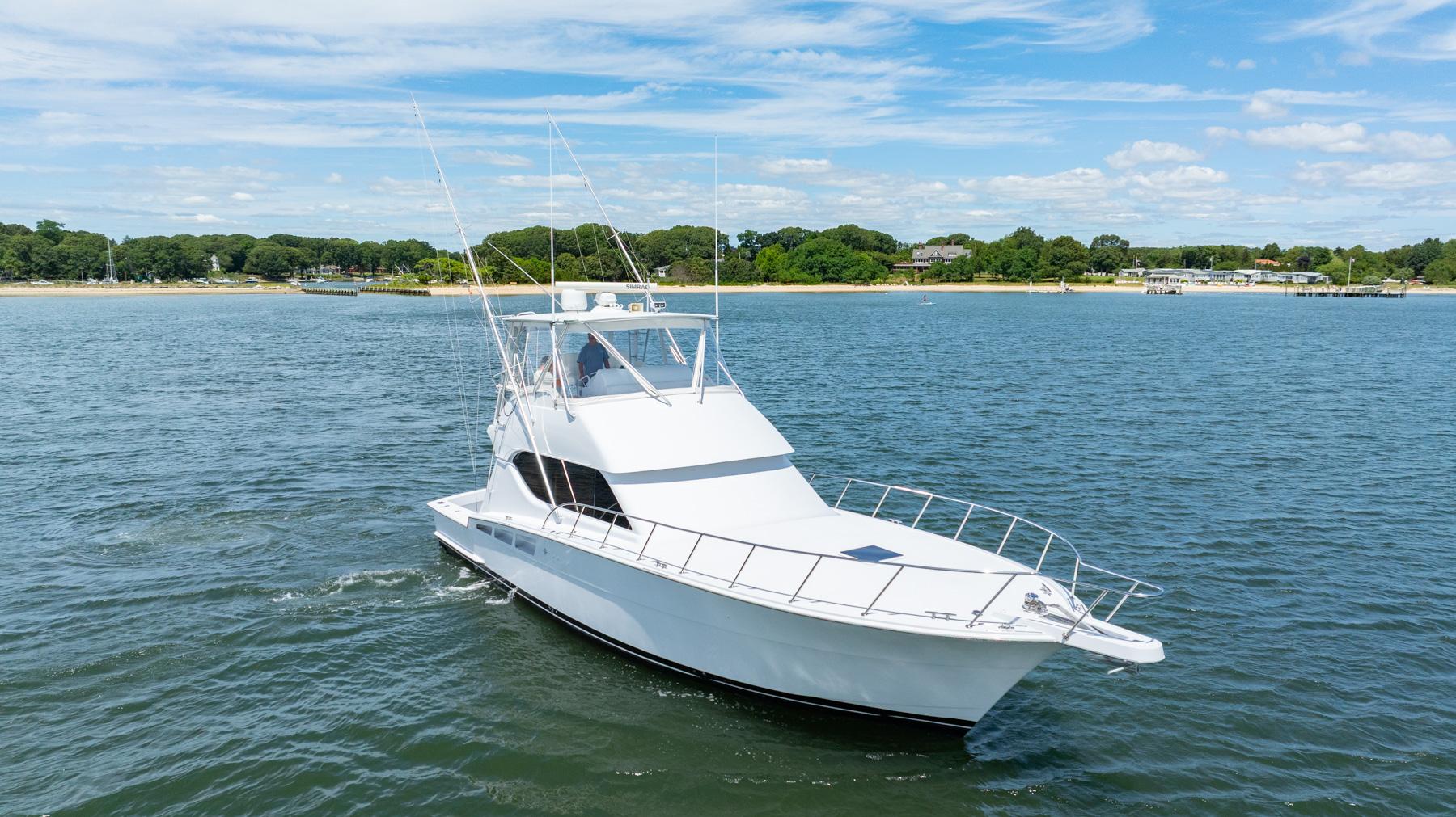 Hatteras 50 Convertible 2001 Hatteras 50 Convertible yacht cruising on a sunny day near the shoreline.