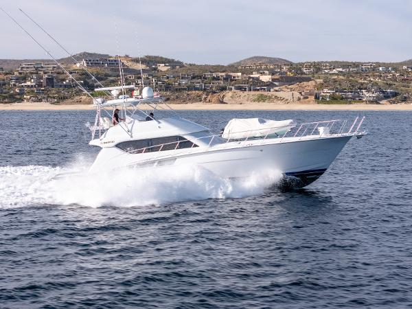 Hatteras 60 Convertible 2003 Hatteras 60 Convertible yacht cruising on open water near coastline.