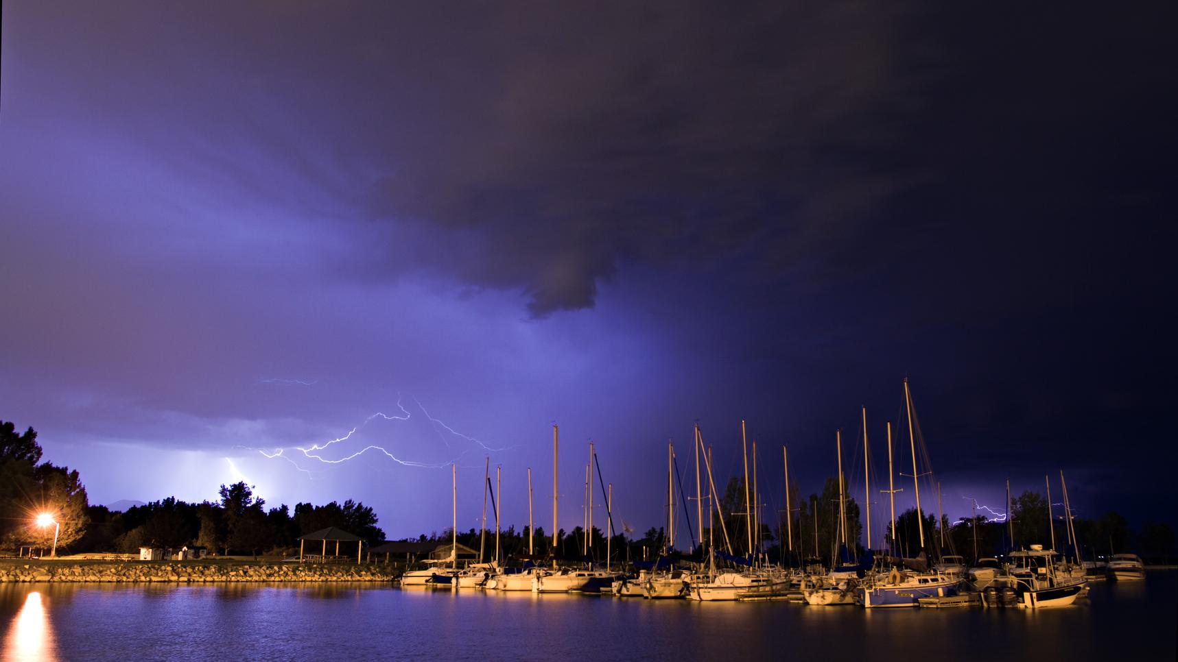 Lightning strikes behind boats in a marina